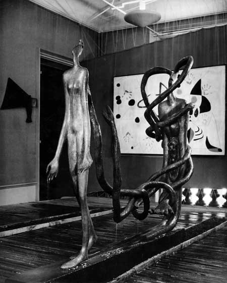 Fig. 6. Willy Maywald, installation view of the Rain Room in the 1947 “Exposition Internationale du Surréalisme,” Galerie Maeght, Paris, with Maria Martins’s sculpture The Road, The Shadow, Too Long, Too Narrow in the foreground and Joan Miró’s Woman in the Night in the background. Vintage gelatin silver print on barite paper, Austrian Frederick and Lillian Kiesler Private Foundation, Vienna ©2013 Association Willy Maywald / Artist Rights Society (ARS), New York / ADAGP, Paris ©2013 Austrian Frederick and Lillian Kiesler Private Foundation, Vienna